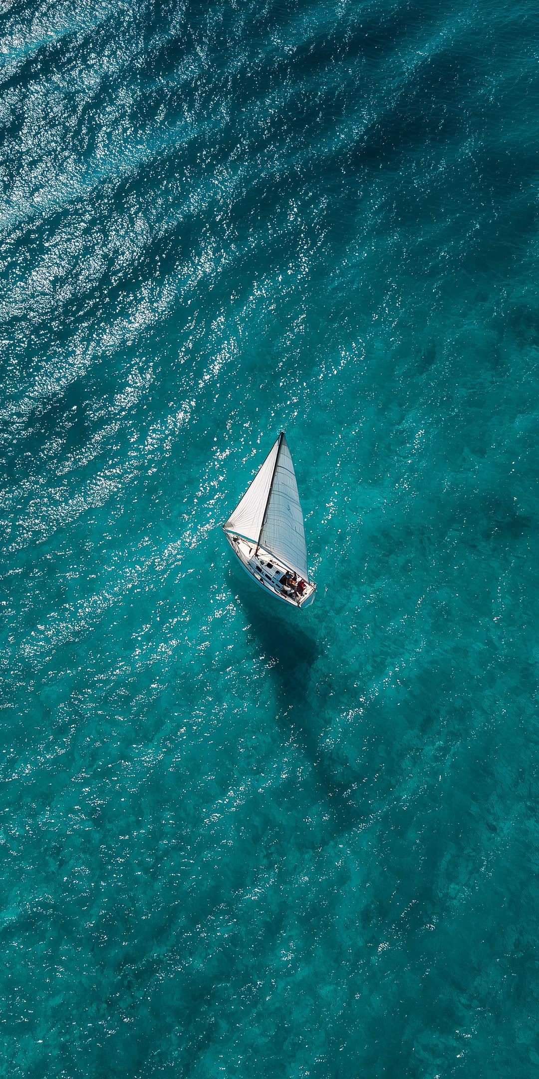 Aerial view of a sailboat in open turquoise water